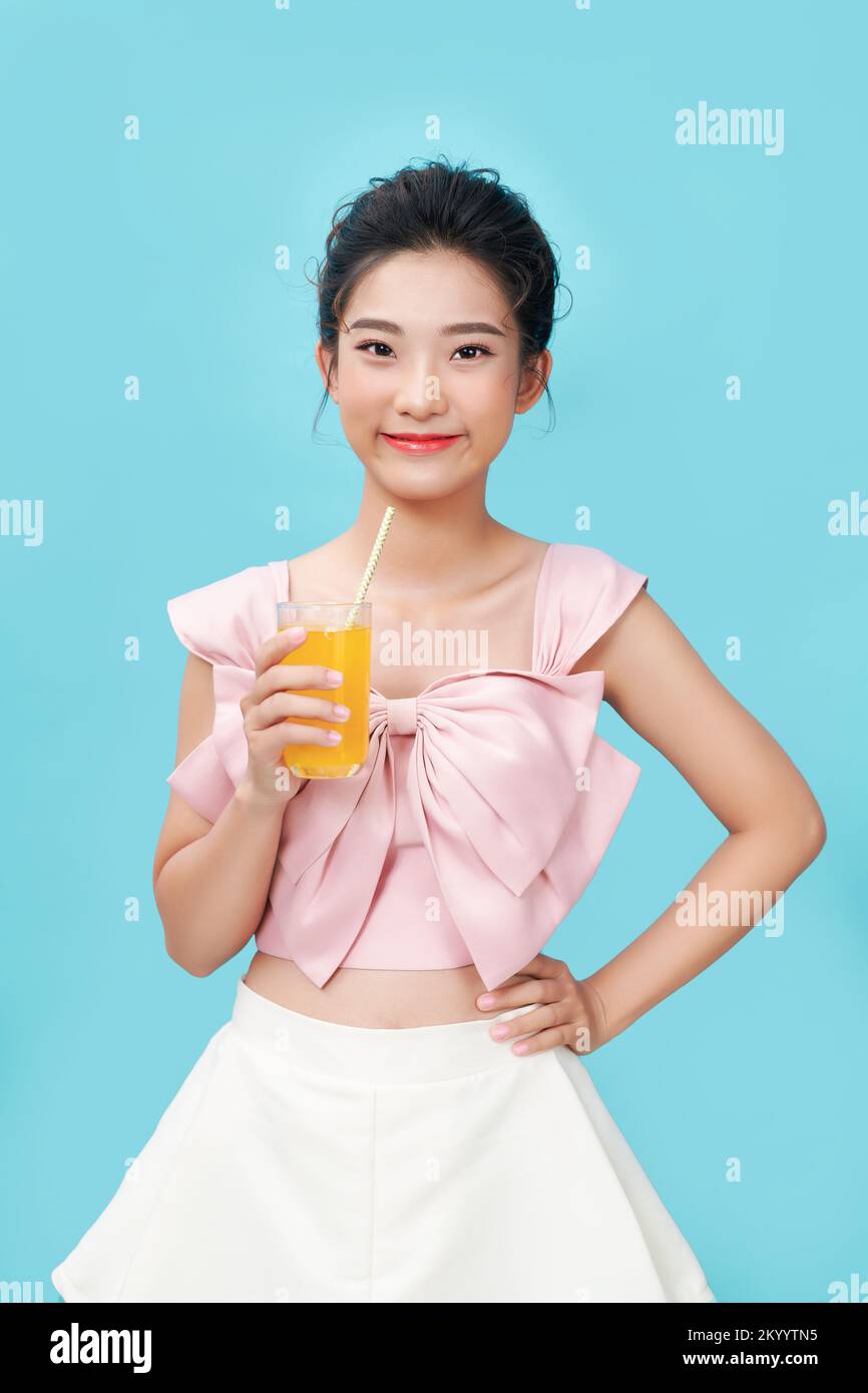 Retrato de una joven feliz bebiendo jugo de naranja durante el desayuno. Foto de stock