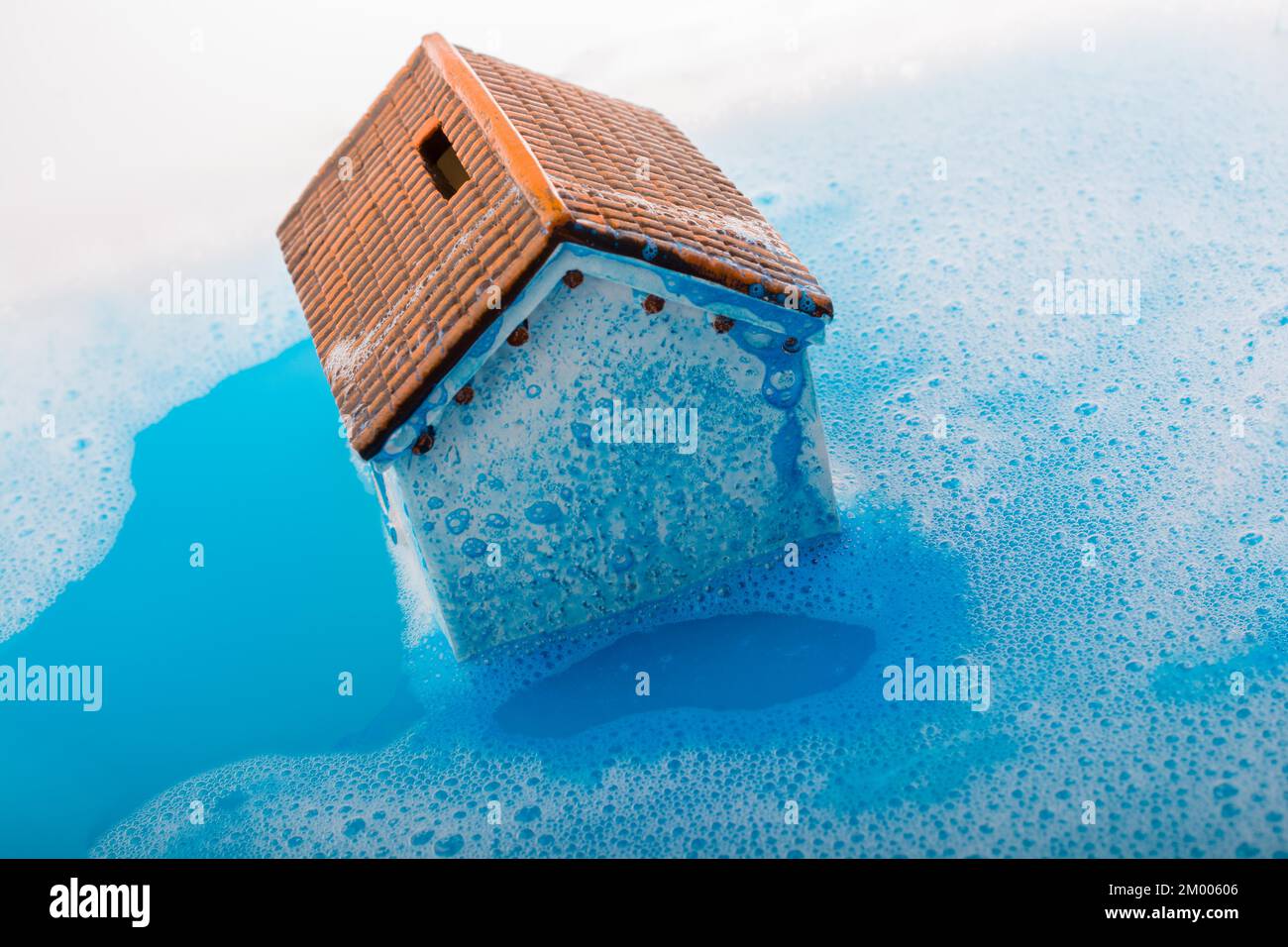 Pequeña casa modelo y un pincel de pintura en agua espumosa Foto de stock