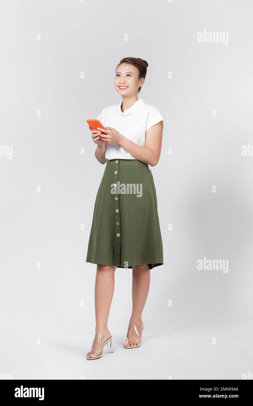 Feliz joven mujer asiática escribiendo mensaje en el smartphone aislado sobre fondo blanco Foto de stock