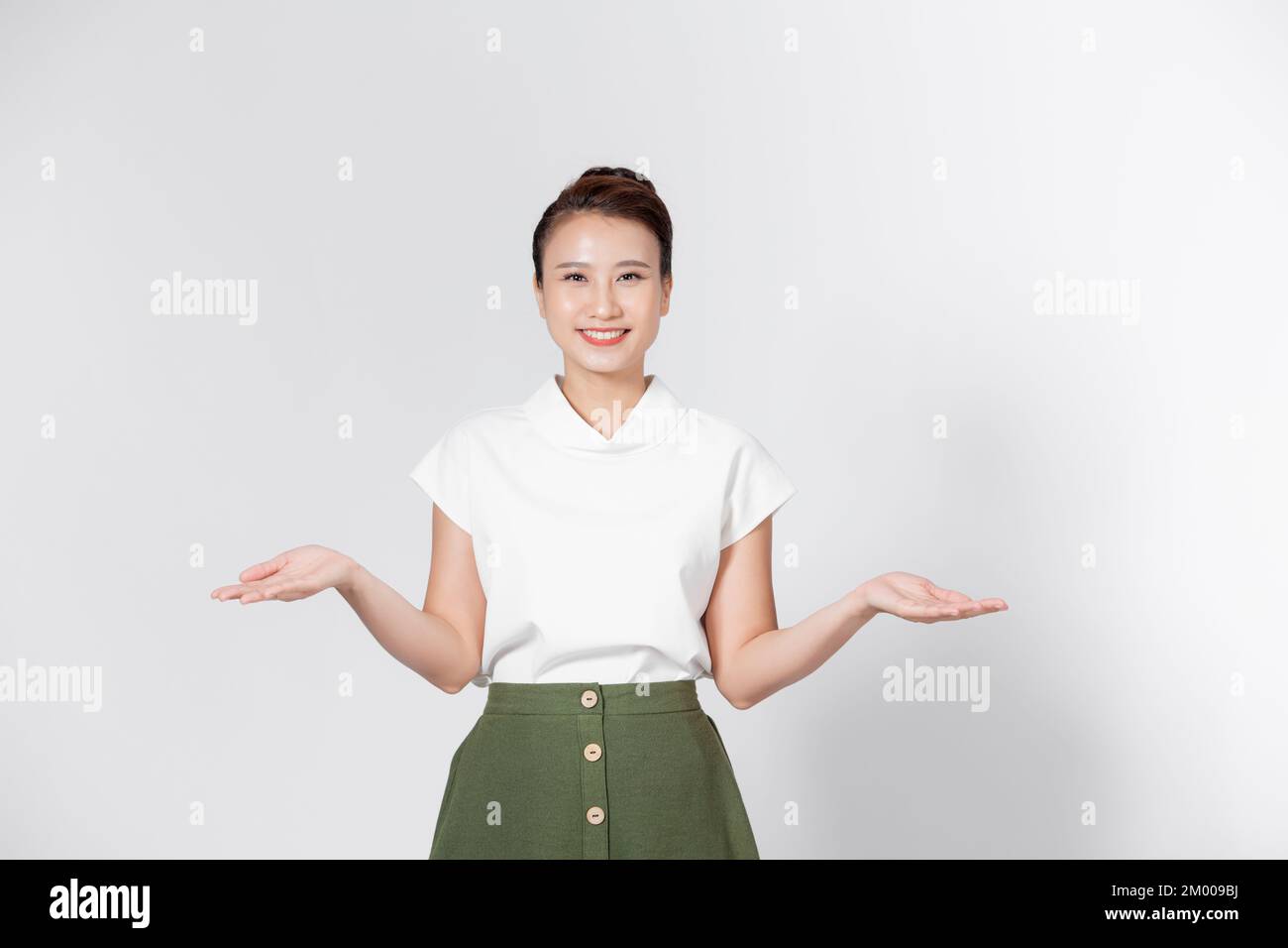 Una joven asiática levantó la mano izquierda y la derecha para comparar o demostrar el producto en el espacio de copia Foto de stock