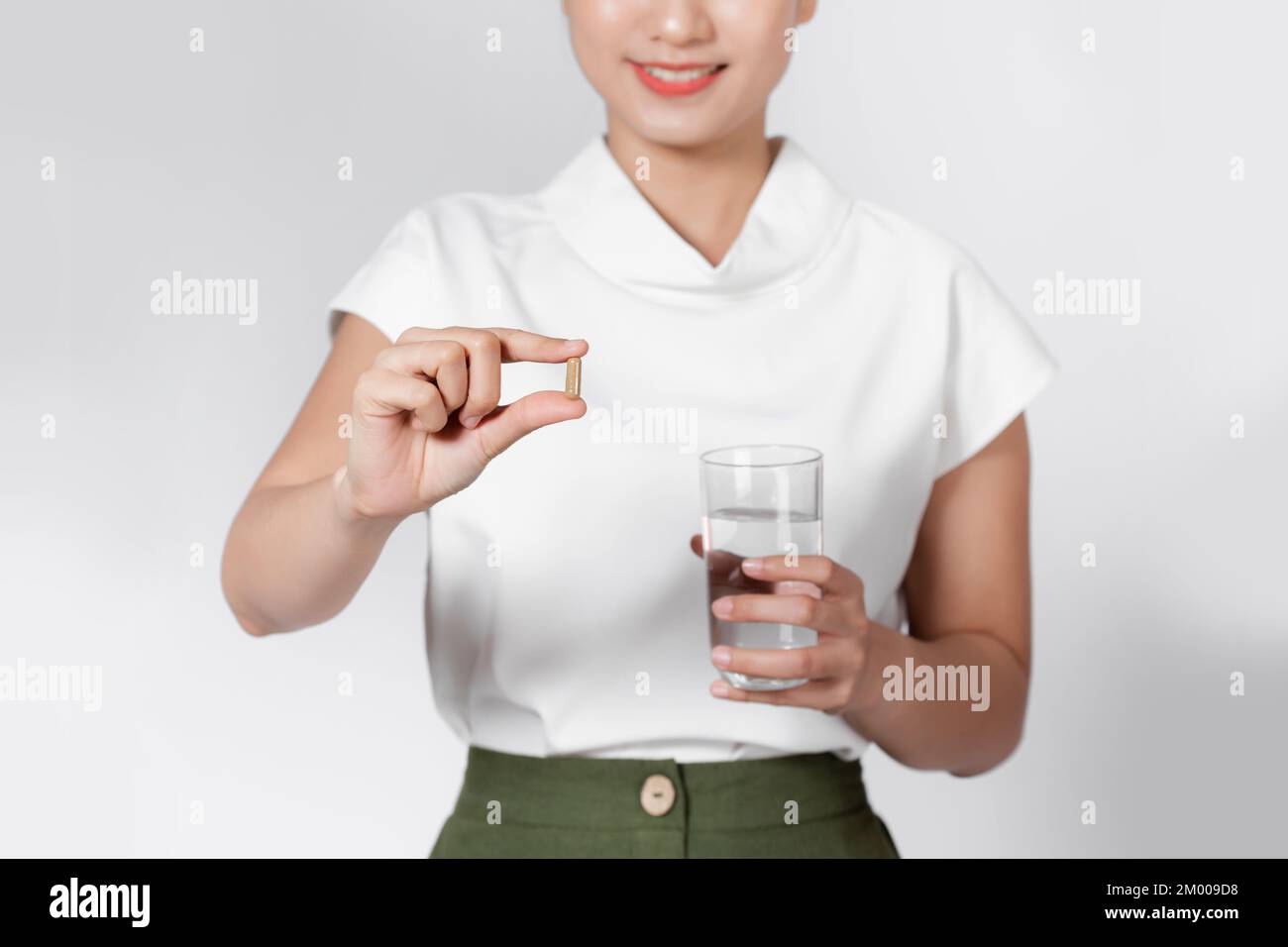 Hermosa mujer sonriente que toma la píldora de la vitamina y la celebración de un vaso de agua dulce en la mañana. Foto de stock
