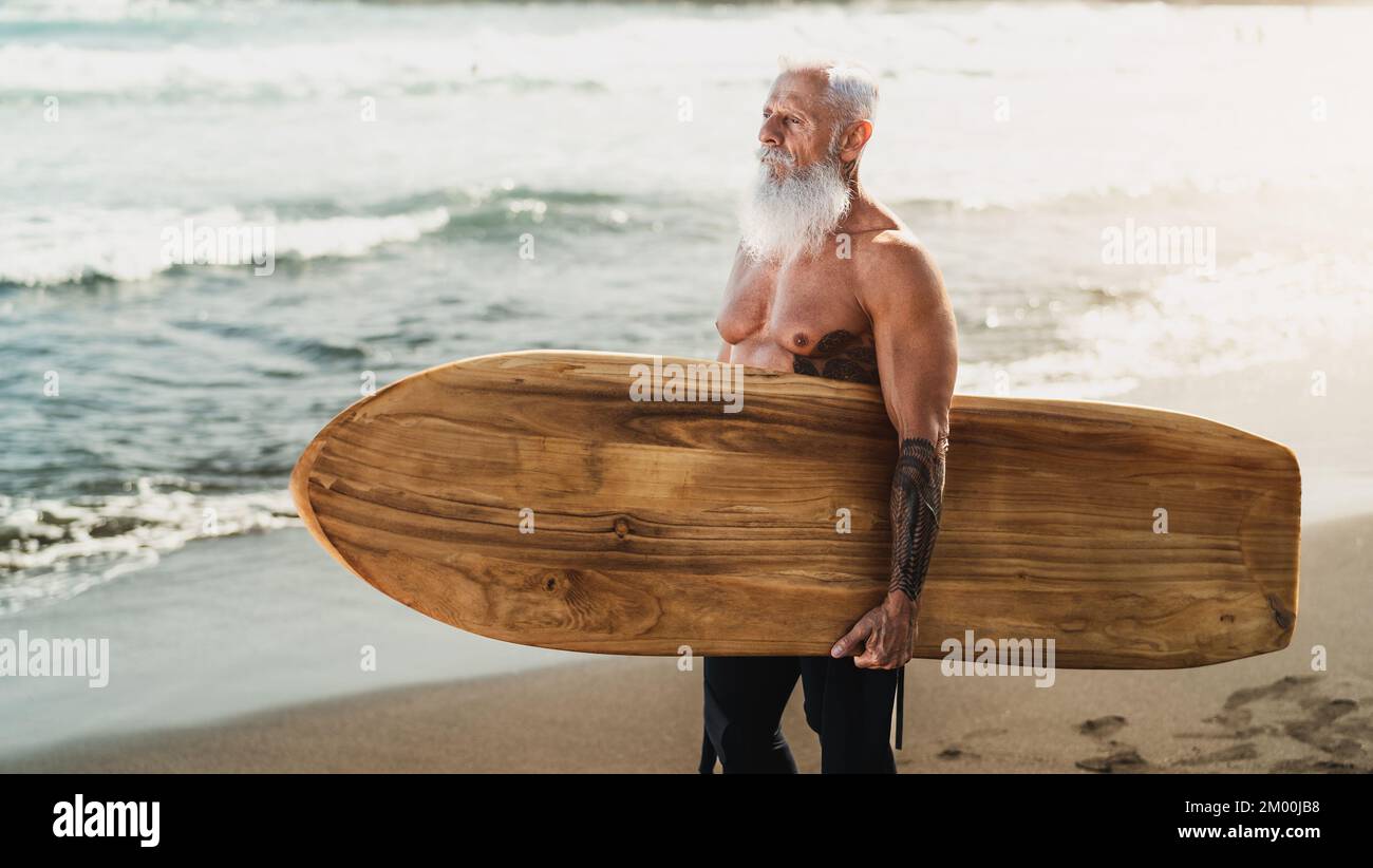 Hombre apto para mayores divertirse practicando surf en la playa tropical - la vida de las personas mayores sanas y el concepto de deporte extremo Foto de stock