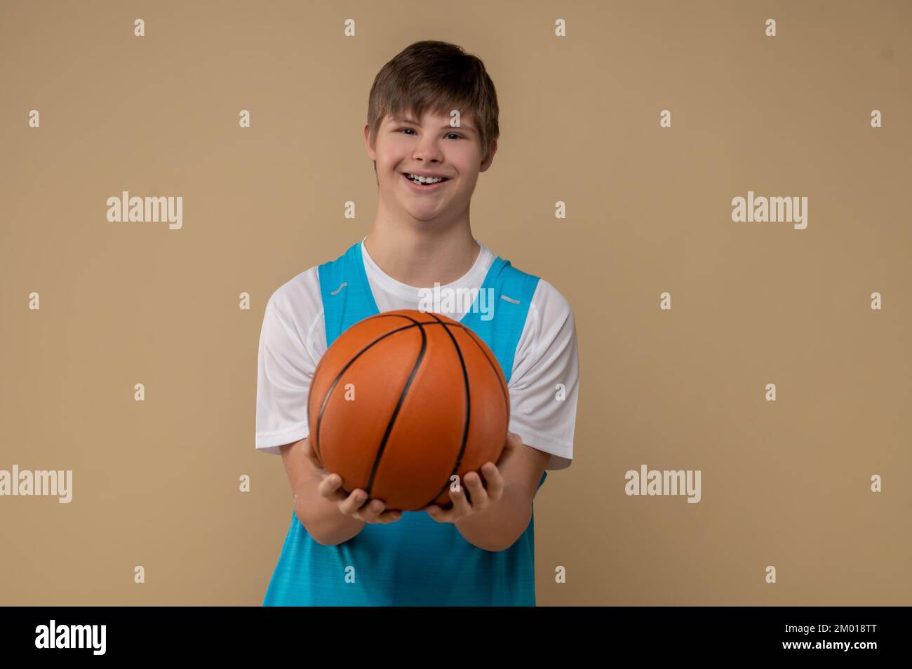 Retrato de un sonriente joven jugador de baloncesto que mostraba su equipo deportivo delante de la cámara. Foto de stock