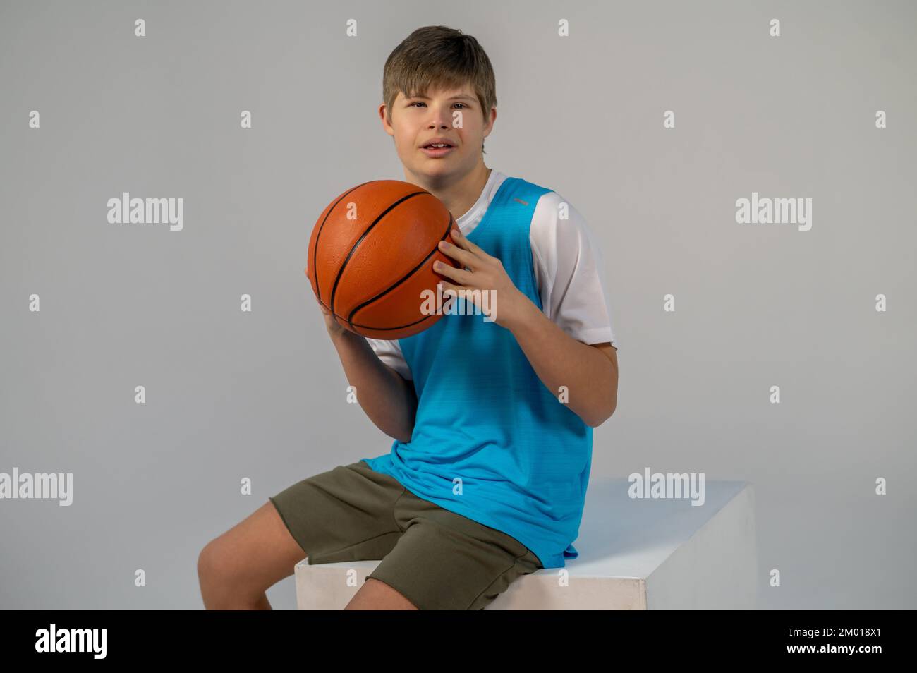 Baloncesto. Niño en pantalones cortos y camiseta azul sentado con