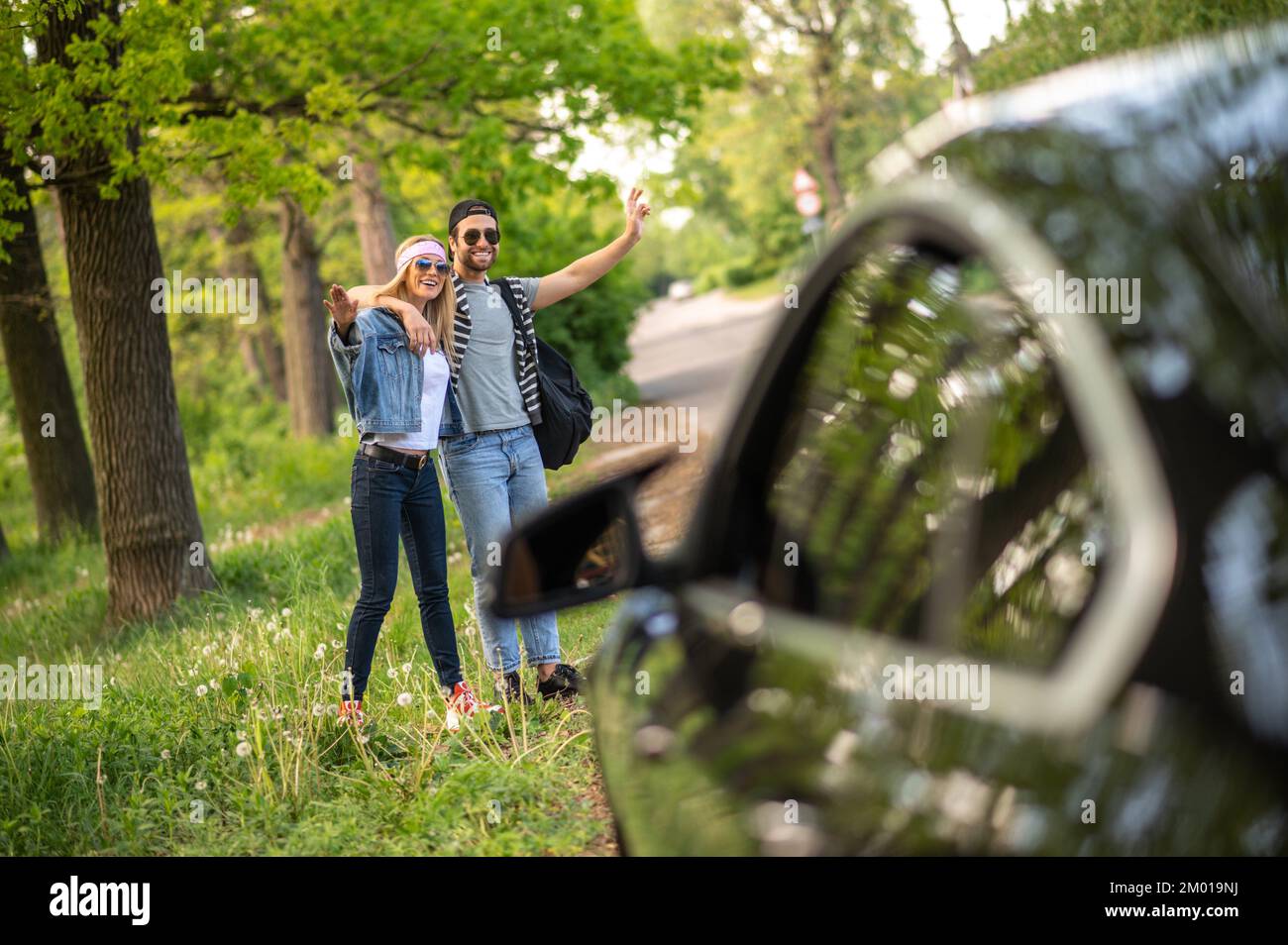 Aventura. Dos personas tratando de detener el coche en el bosque y luciendo alegre. Foto de stock