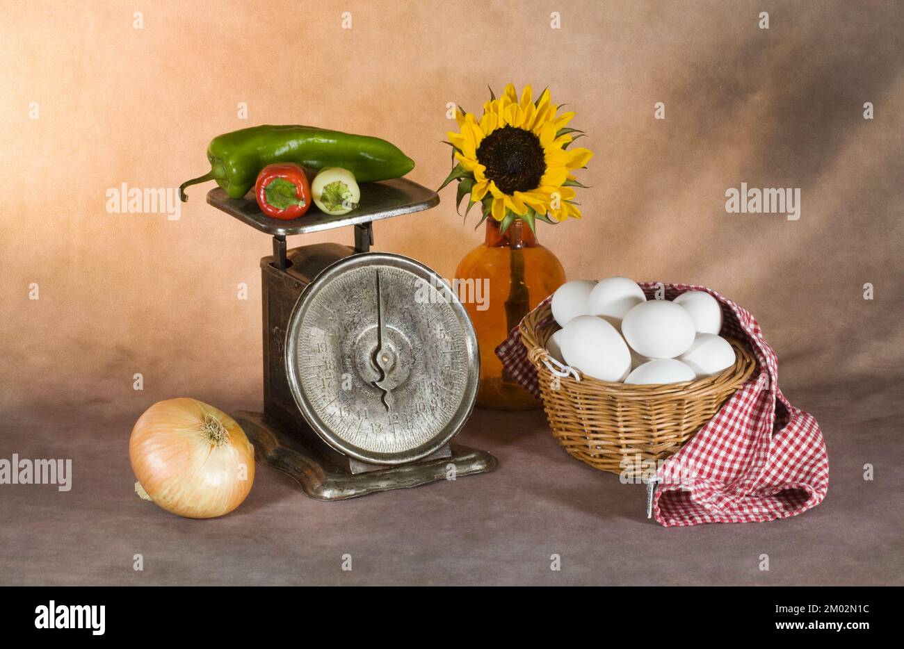Fotografía artística de una docena de huevos en una cesta, verduras a una escala antigua y un girasol en una botella vintage. Foto de stock