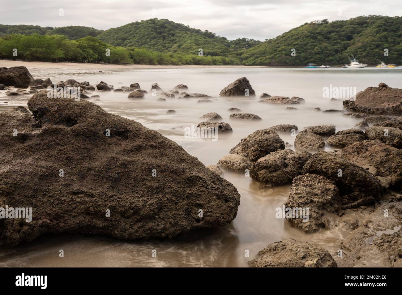 Piedras marrones en la playa del mar con el agua suave sedosa Foto de stock