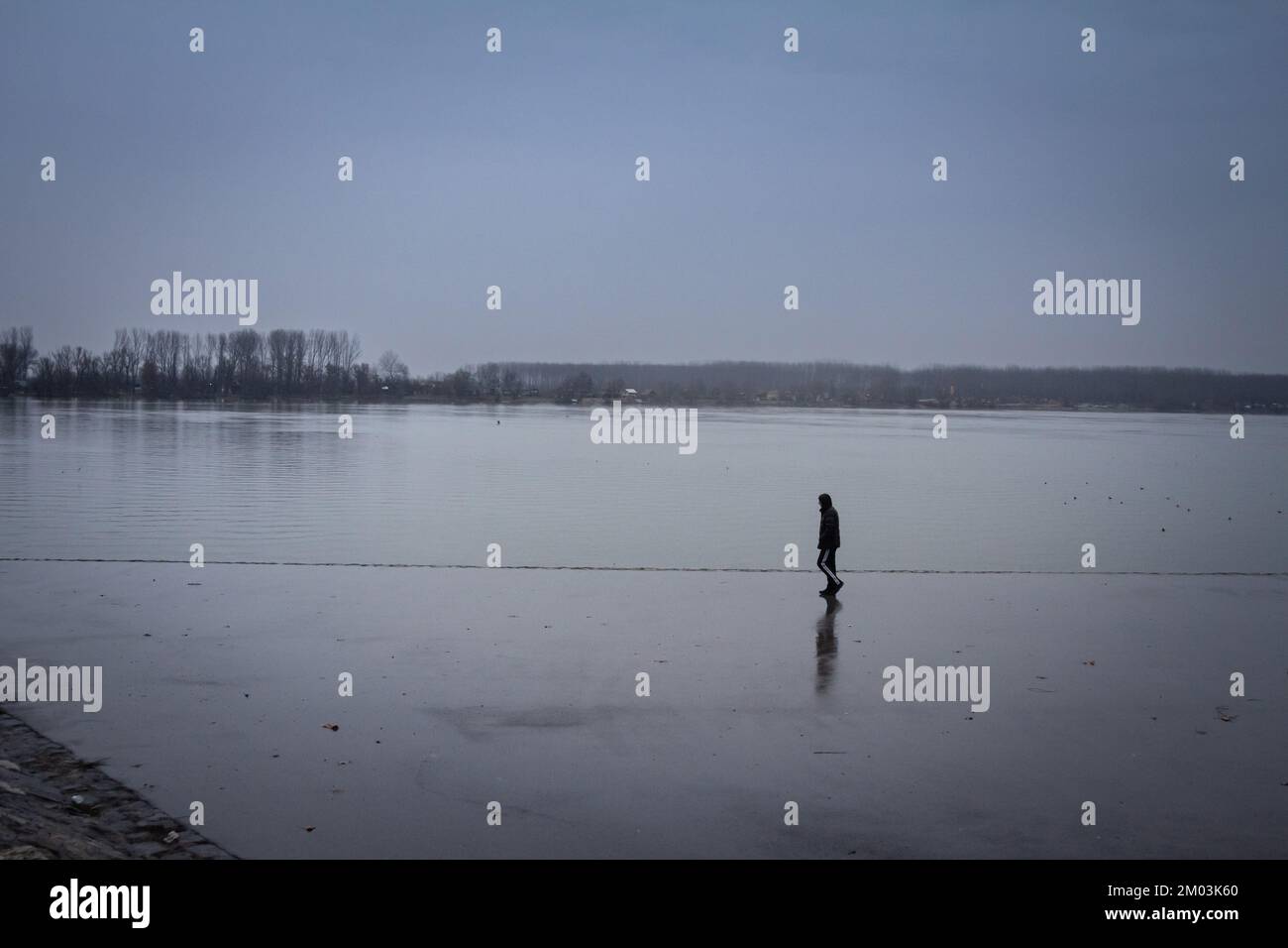Imagen de un hombre que tiene un paseo solo cerca del río Danubio, mientras que la mayor parte del paisaje se está desvaneciendo debido a un fuerte smog y la lluvia, en el Zemun subtropical Foto de stock