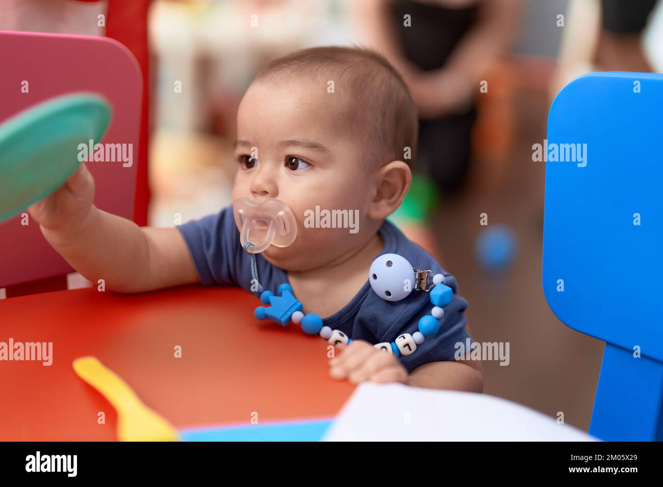 Niño chino adorable usando un chupete sosteniendo un plato de juguete en el  jardín de infancia Fotografía de stock - Alamy