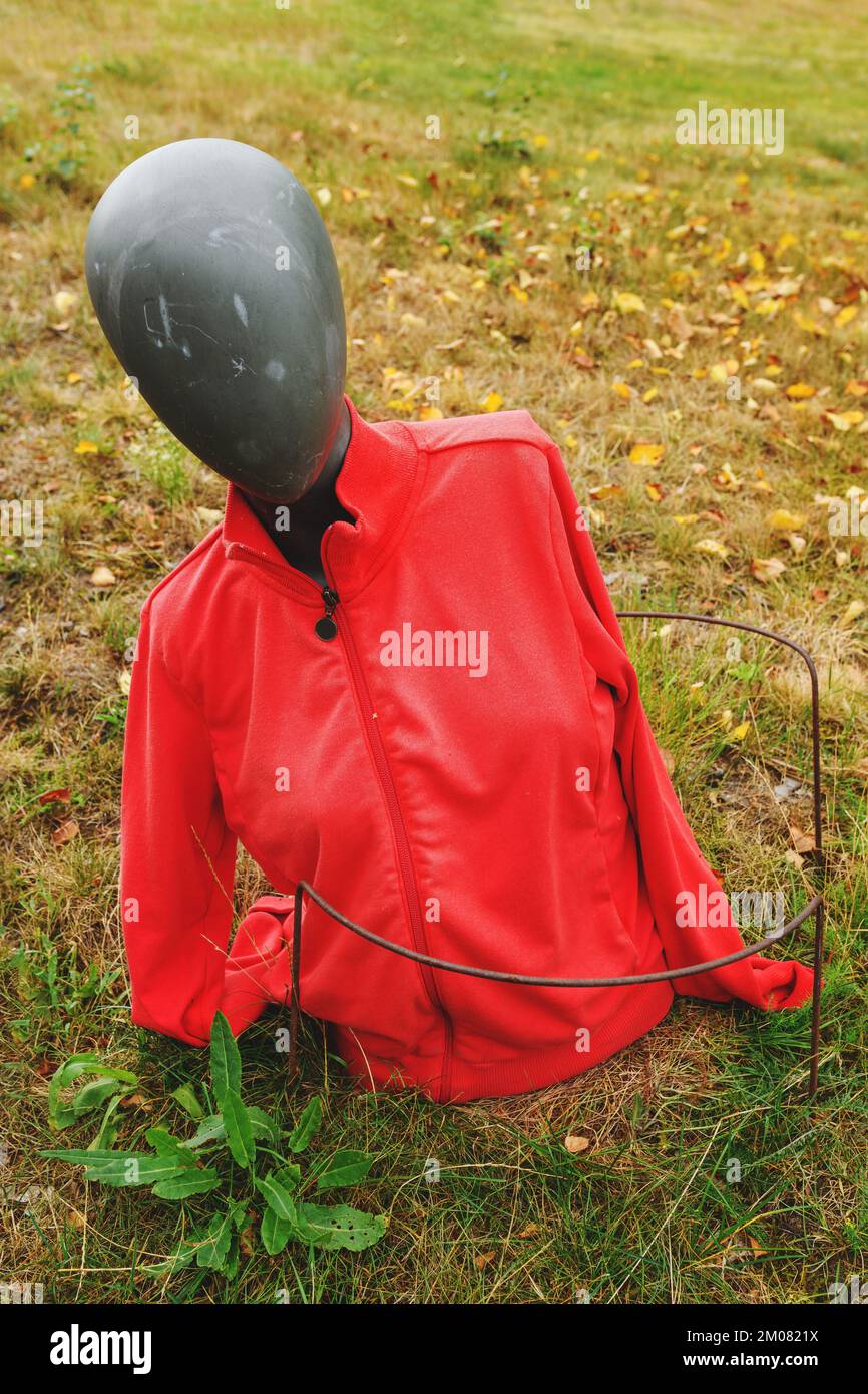 Maniquí viejo descartado con chaqueta roja en parque público, imagen conceptual con enfoque selectivo Foto de stock