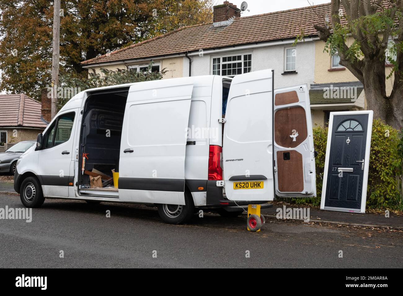 Furgoneta blanca aparcada fuera de las casas con una nueva puerta de sustitución lista para encajar, Reino Unido Foto de stock