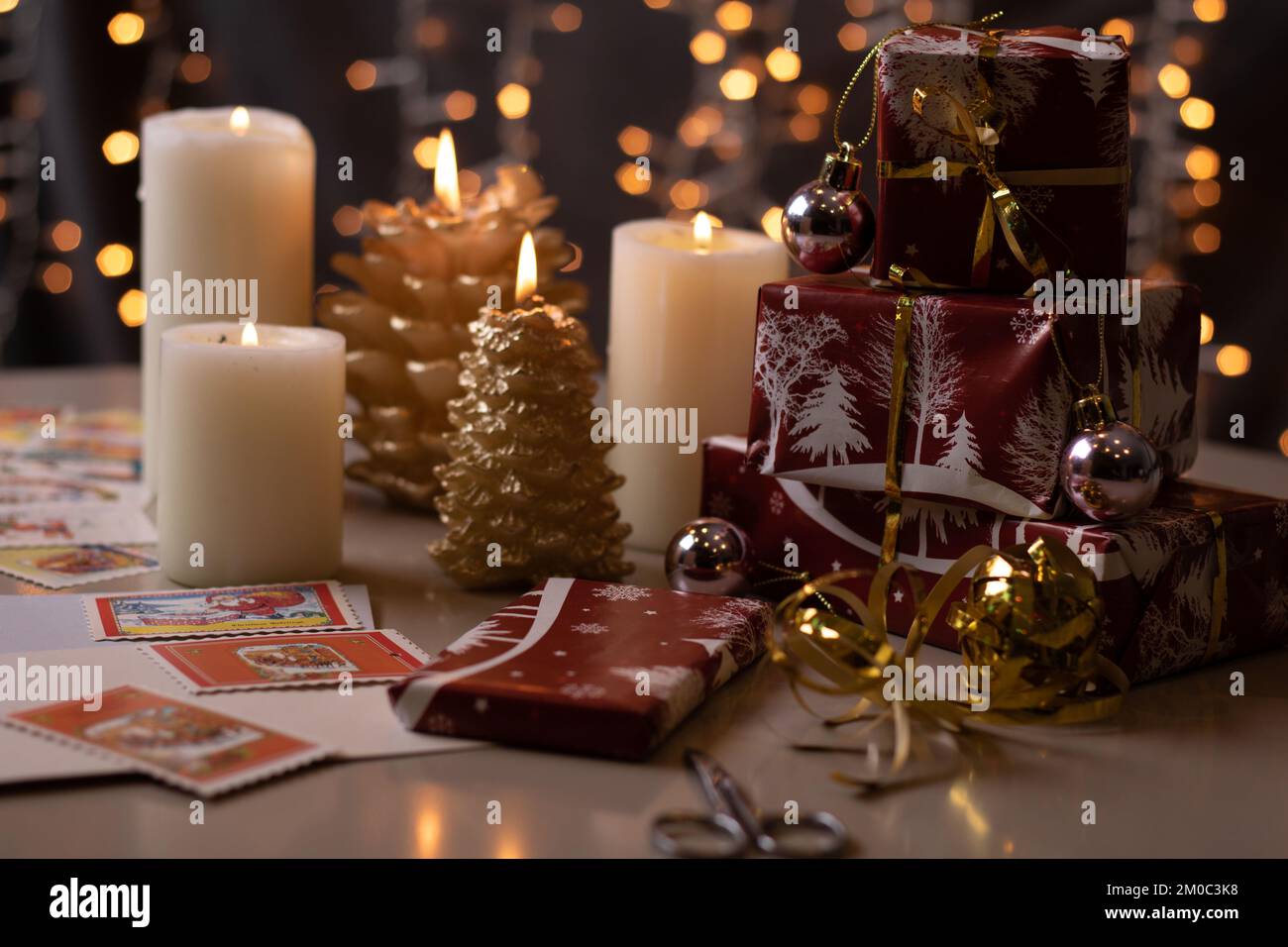 los regalos envueltos en la foto se colocan en la mesa junto a velas encendidas Foto de stock