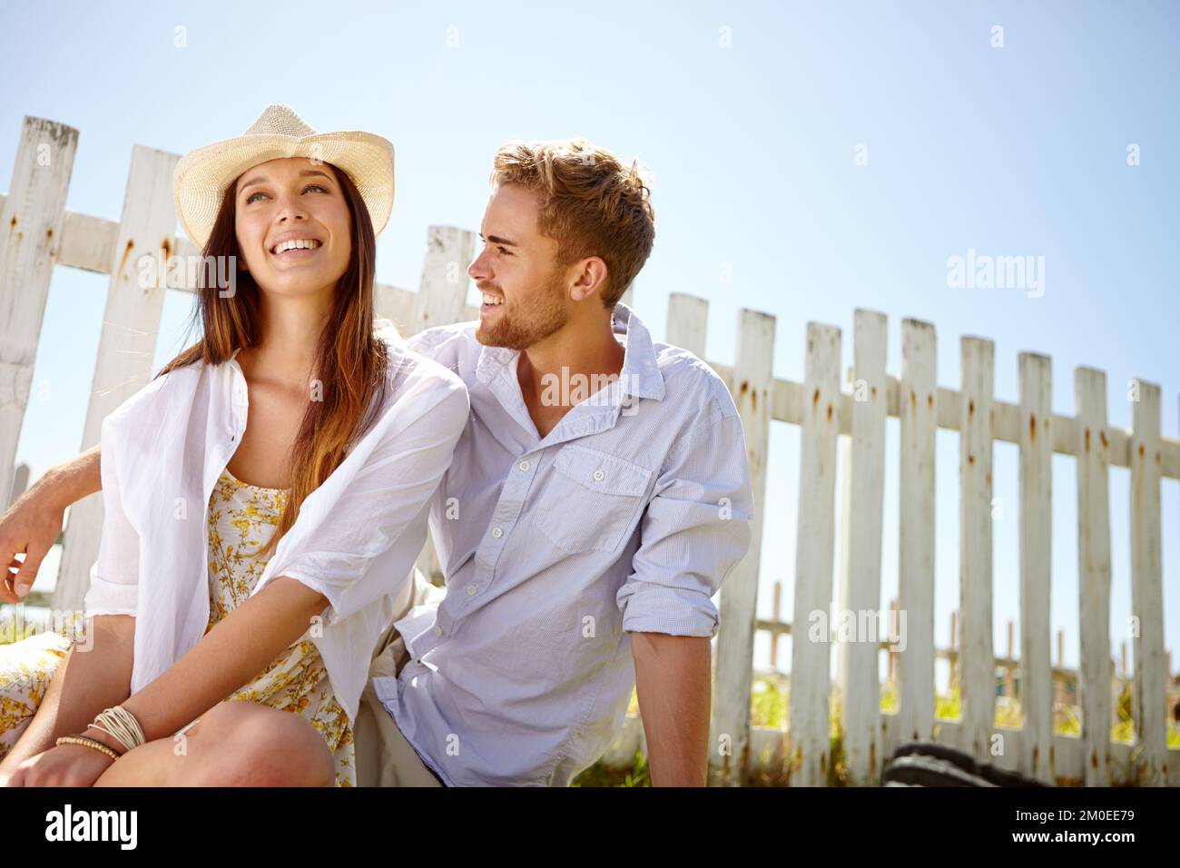 Días de verano de ensueño. Una atractiva pareja joven riendo rapidamente mientras estaba sentado afuera. Foto de stock
