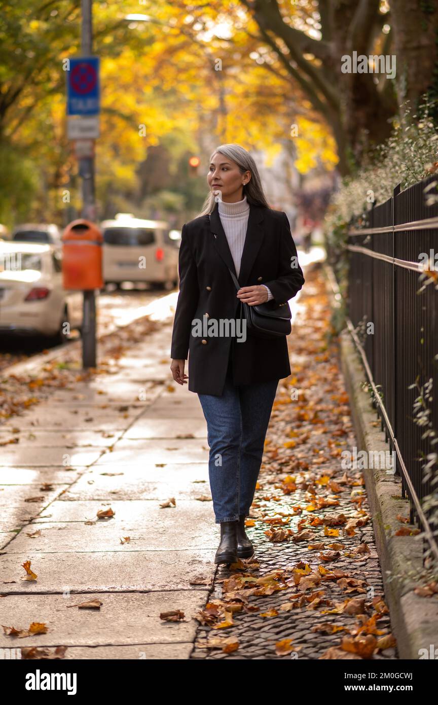 Mujer bastante madura caminando en el parque de otoño Foto de stock