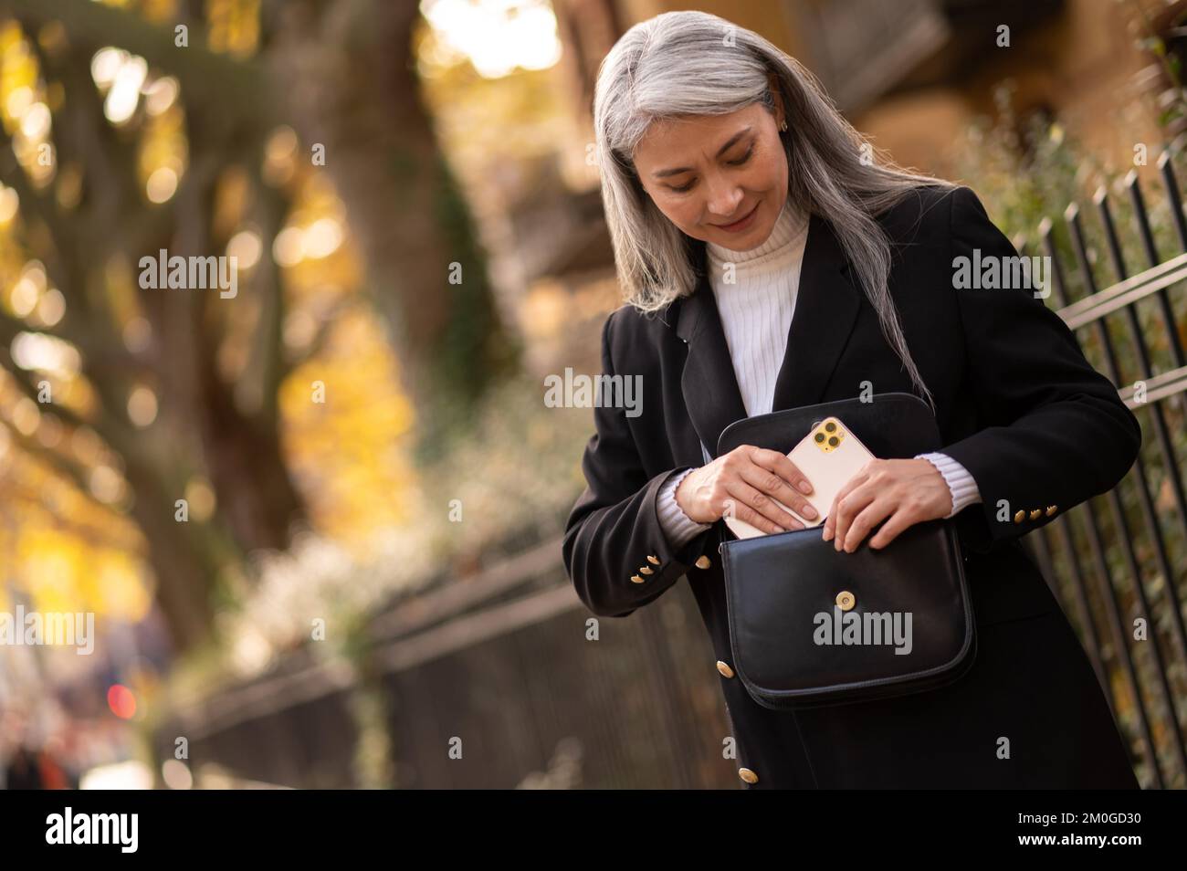 Mujer de mediana edad de pelo largo con un smartphone que parece anticipado Foto de stock
