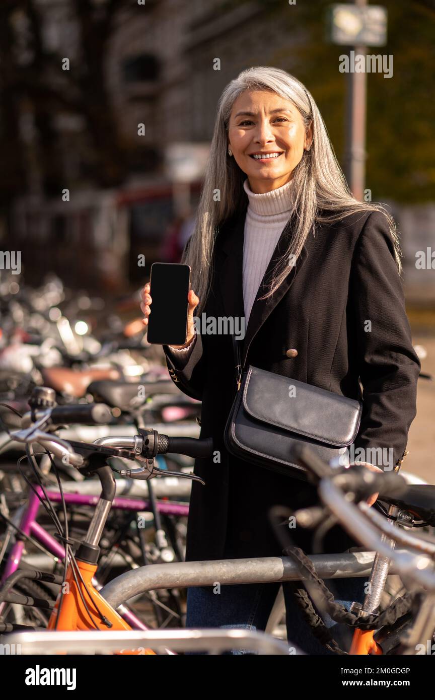 Sonriente mujer madura alquilando una bicicleta de calle Foto de stock