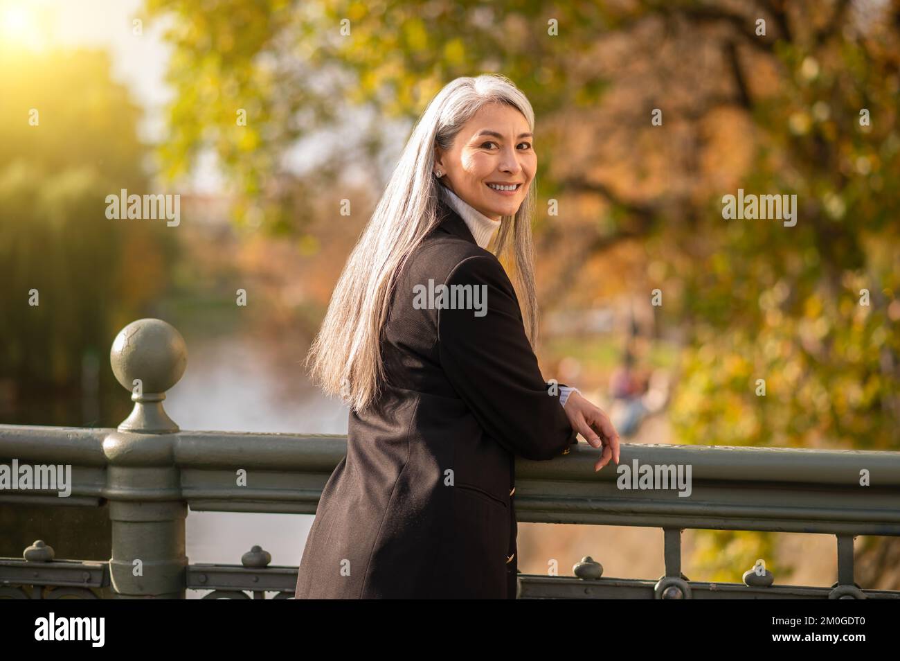 Mujer bastante madura de pelo largo parada en el puente Foto de stock