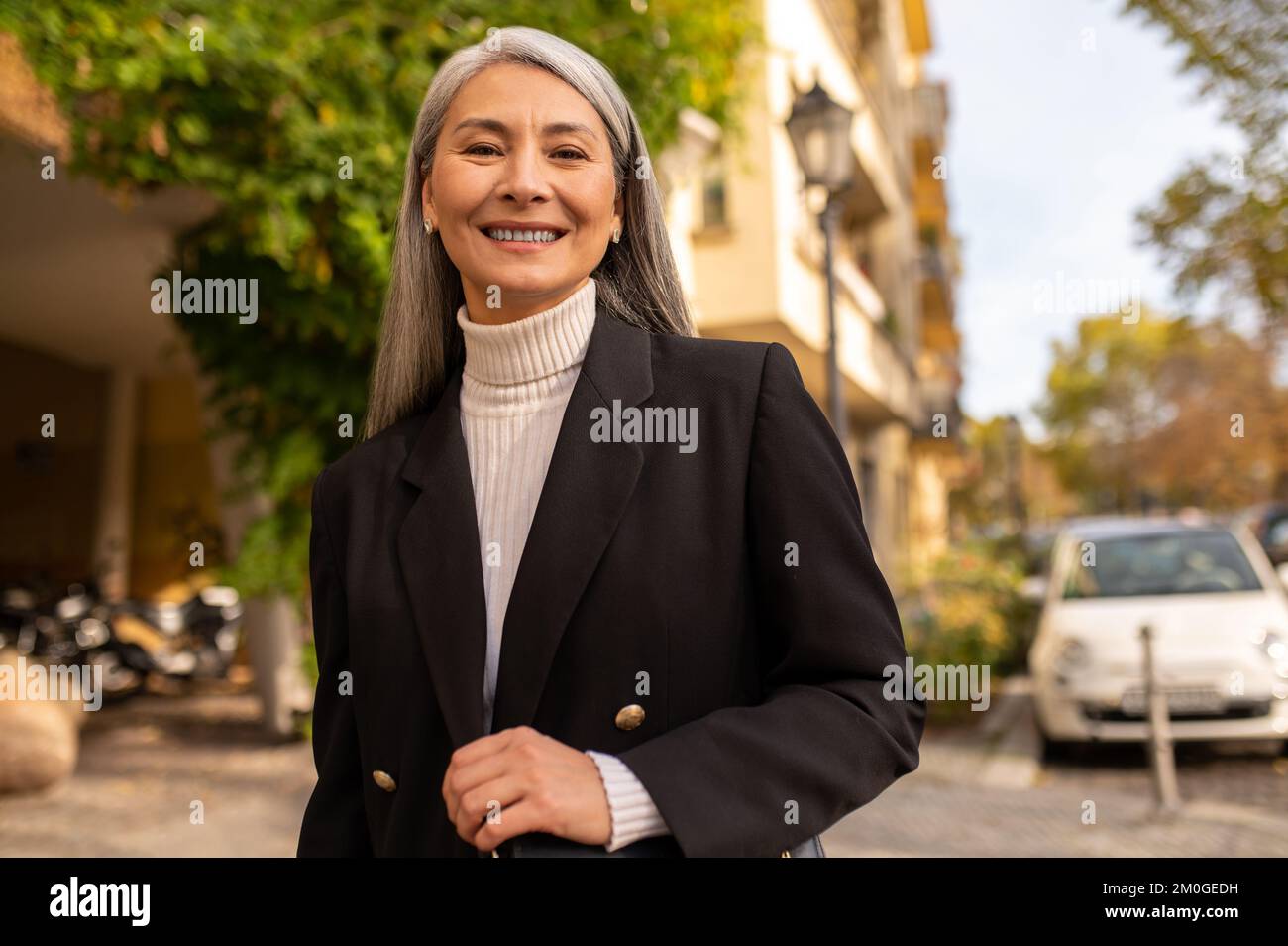 Sonriendo mujer bonita con un abrigo negro en la calle de la ciudad Foto de stock