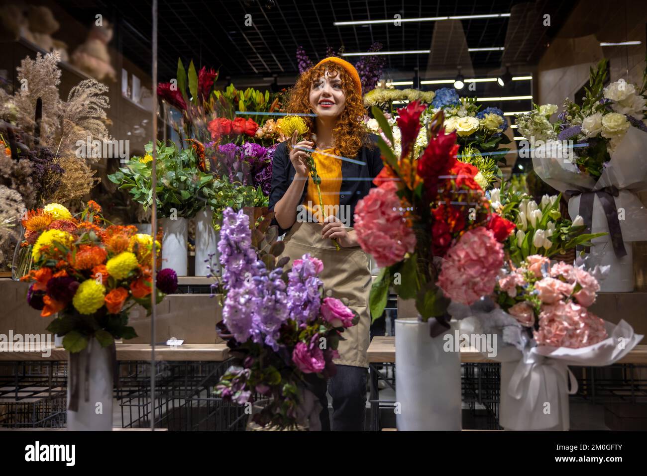 Florista lindo en una floristería que parecía disfrutada Foto de stock