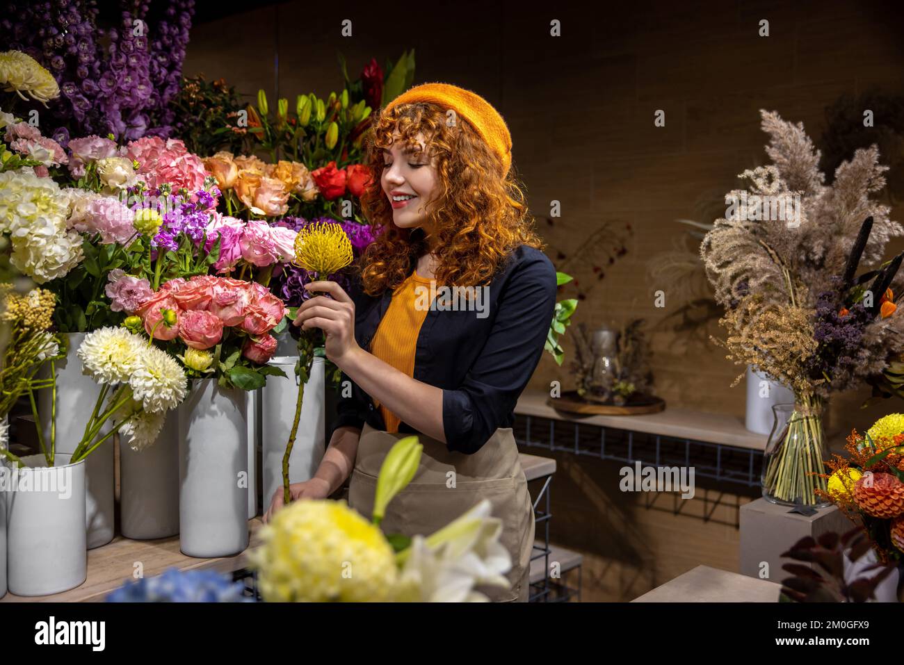 Florista lindo en una floristería que parecía disfrutada Foto de stock