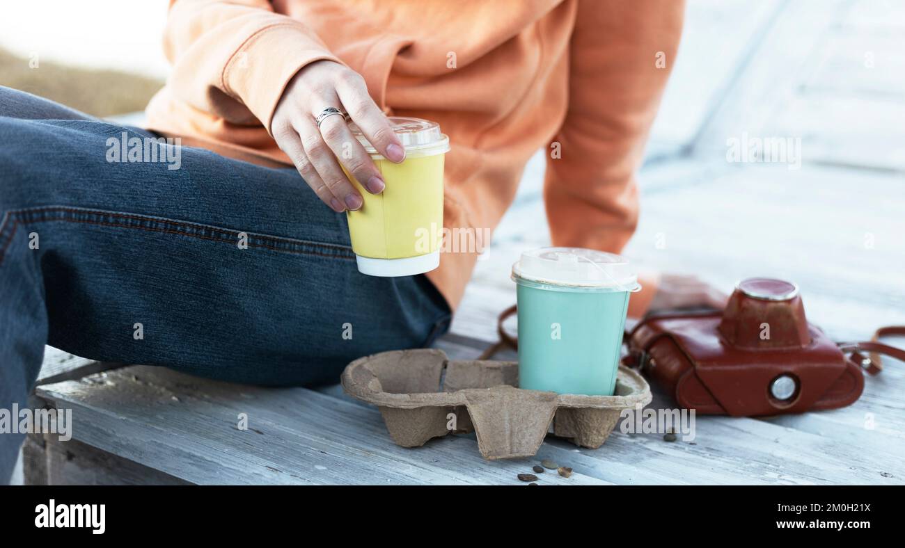 chica sosteniendo vasos de café a la luz del atardecer Foto de stock