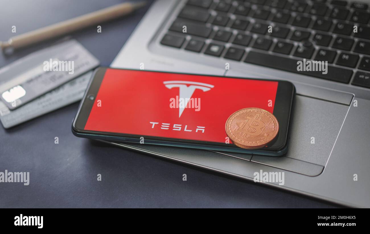 Dobrich, Bulgaria – 2022 de noviembre de 26: Teléfono móvil en un portátil con el logotipo de Tesla, Bitcoin y tarjetas de crédito. Concepto editorial ilustrativo Foto de stock