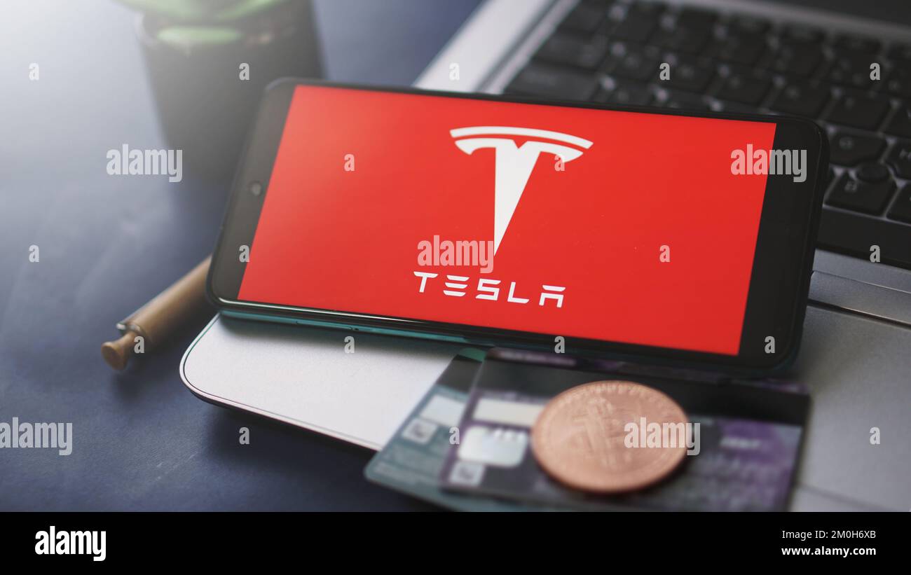 Dobrich, Bulgaria – 2022 de noviembre de 26: Teléfono móvil en un portátil con el logotipo de Tesla, Bitcoin y tarjetas de crédito. Concepto editorial ilustrativo Foto de stock