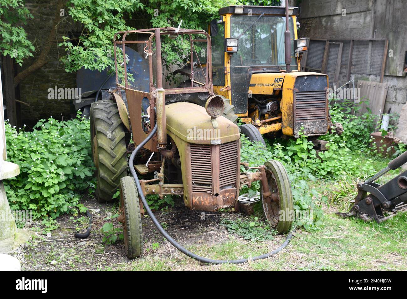 Tractores agrícolas retirados en una granja en Dorset. El pequeño tractor Ferguson en primer plano fue diseñado por Henry Ferguson y estaba en el producto Foto de stock