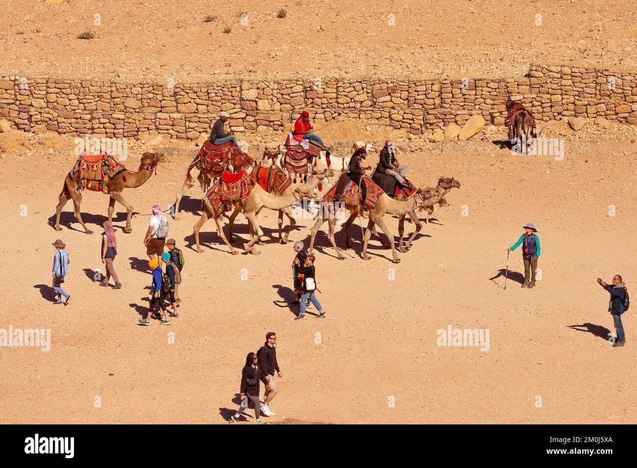 Petra, Jordania - 3 de noviembre de 2022: Jinetes de camellos beduinos y turistas vista de alto ángulo en la antigua ciudad de Petra Foto de stock