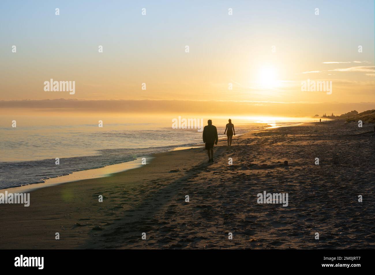 Playa de Papamoa en el sol de la mañana irreconocible caminantes de la mañana en silueta. Foto de stock