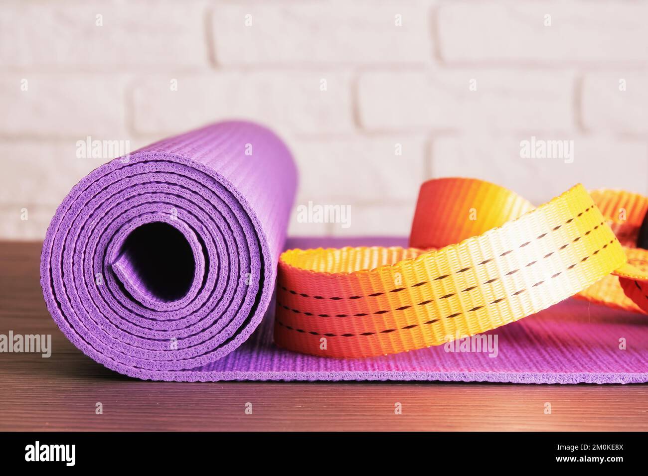 Alfombrilla de fitness púrpura y cuerda naranja en la sala de fitness con pared de ladrillo. Equipamiento deportivo y de ejercicio Foto de stock