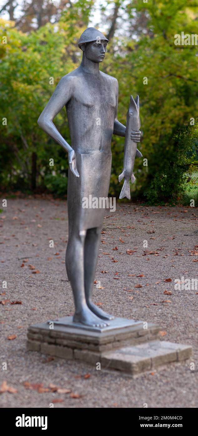 La estatua de estilo moderno de un niño sosteniendo un pez en los terrenos del Hotel Anna Villa en el lago Balaton en Balatonfoldvar Balatonföldvár (Földwahr) es un popula Foto de stock