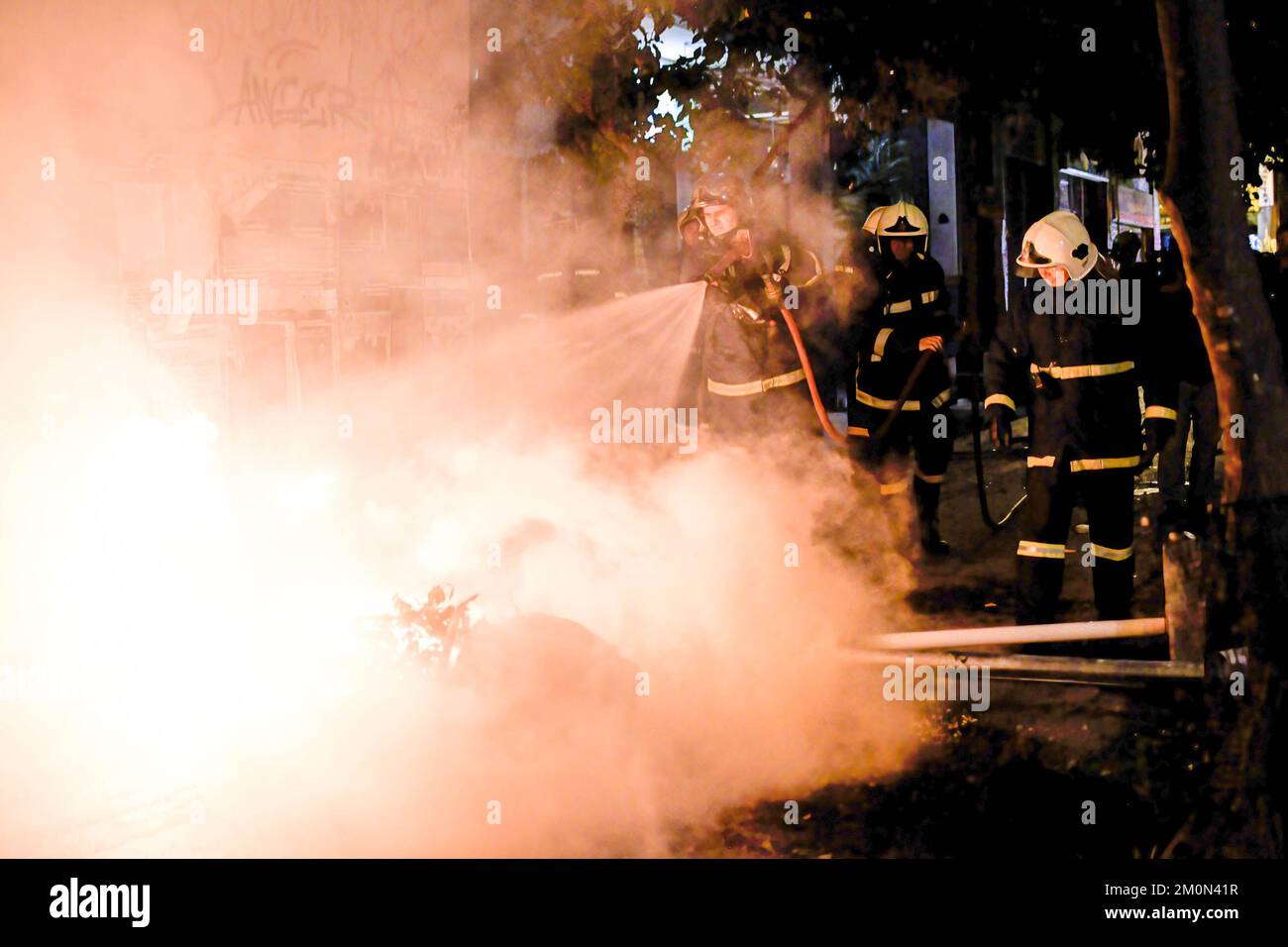 Durante una manifestación, se ve a los bomberos extinguiendo una barrera de neumáticos en llamas creada por grupos de protesta anarquistas. Miles de anarquistas organizaron una protesta en memoria de Alexis Grigoropoulos, un niño de 15 años que fue baleado en blanco en 2008 por un policía. Más tarde se enfrentaron con la policía mientras les lanzaban un cóctel molotov. (Foto de Iason Raissis / SOPA Images/Sipa USA) Foto de stock