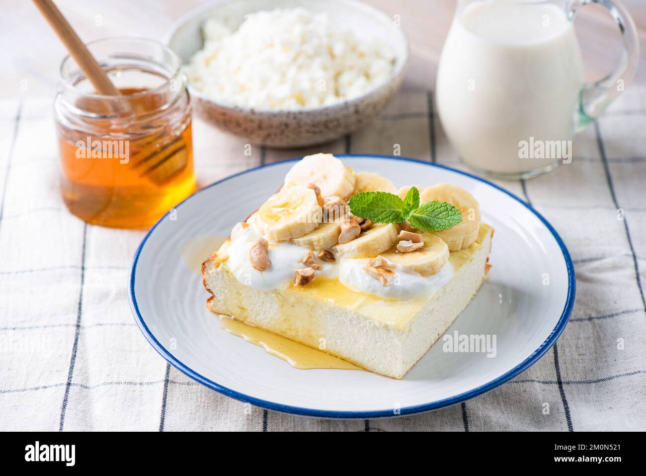 Pastel de queso, cazuela de queso Zapekanka servido con rodajas de plátano, nueces picadas, miel y yogur griego. Desayuno saludable rico en Calciu Foto de stock