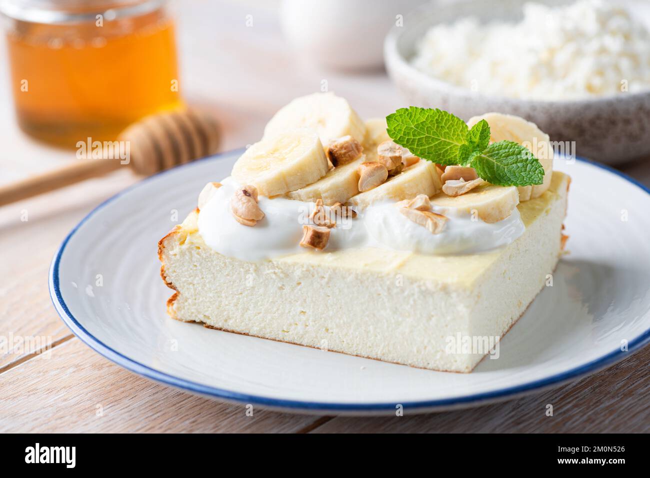 Cazuela de queso cottage, pastel de queso servido con yogur griego, plátano y frutos secos. Tarta de desayuno dulce Foto de stock