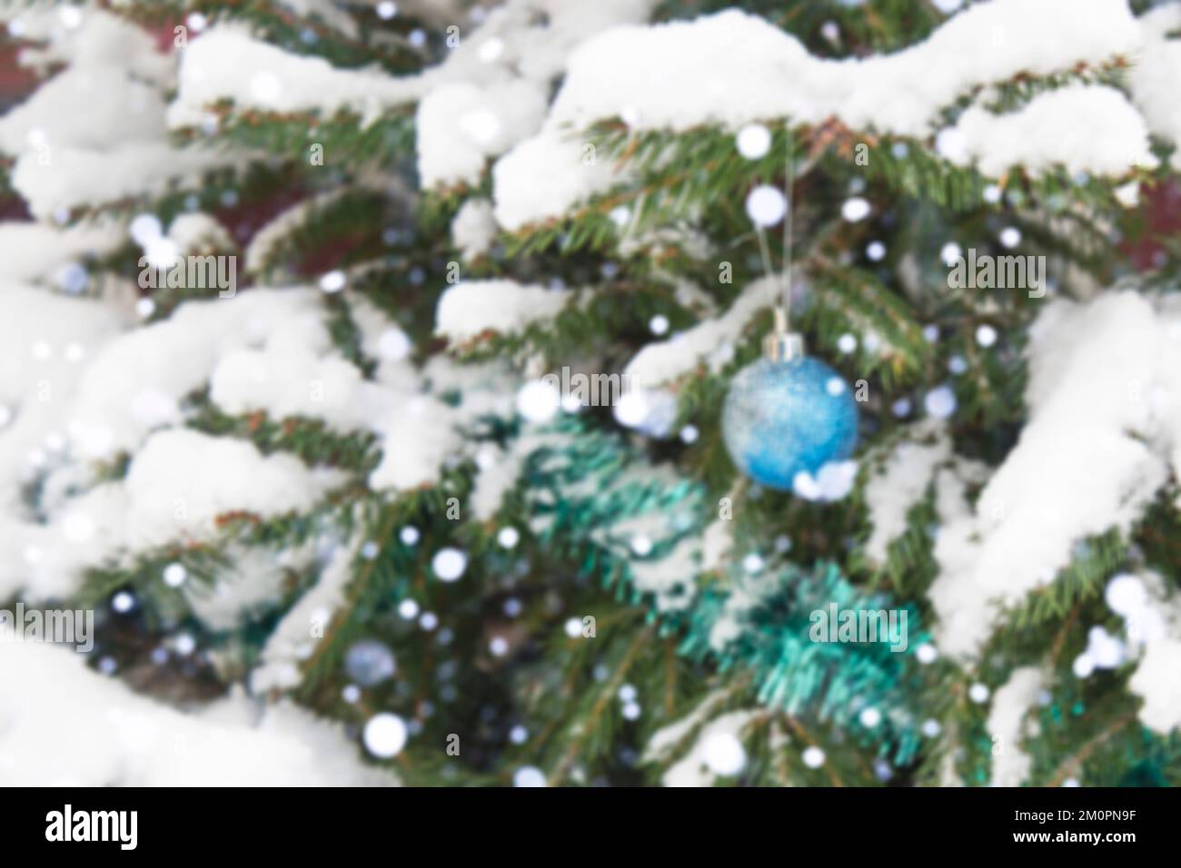 El fondo no tiene nitidez, no hay enfoque. Invierno, festivo, fondo de Navidad. Un árbol de Navidad decorado con juguetes y espumillón. Nevadas. Caída de nieve. Bokeh. Foto de stock
