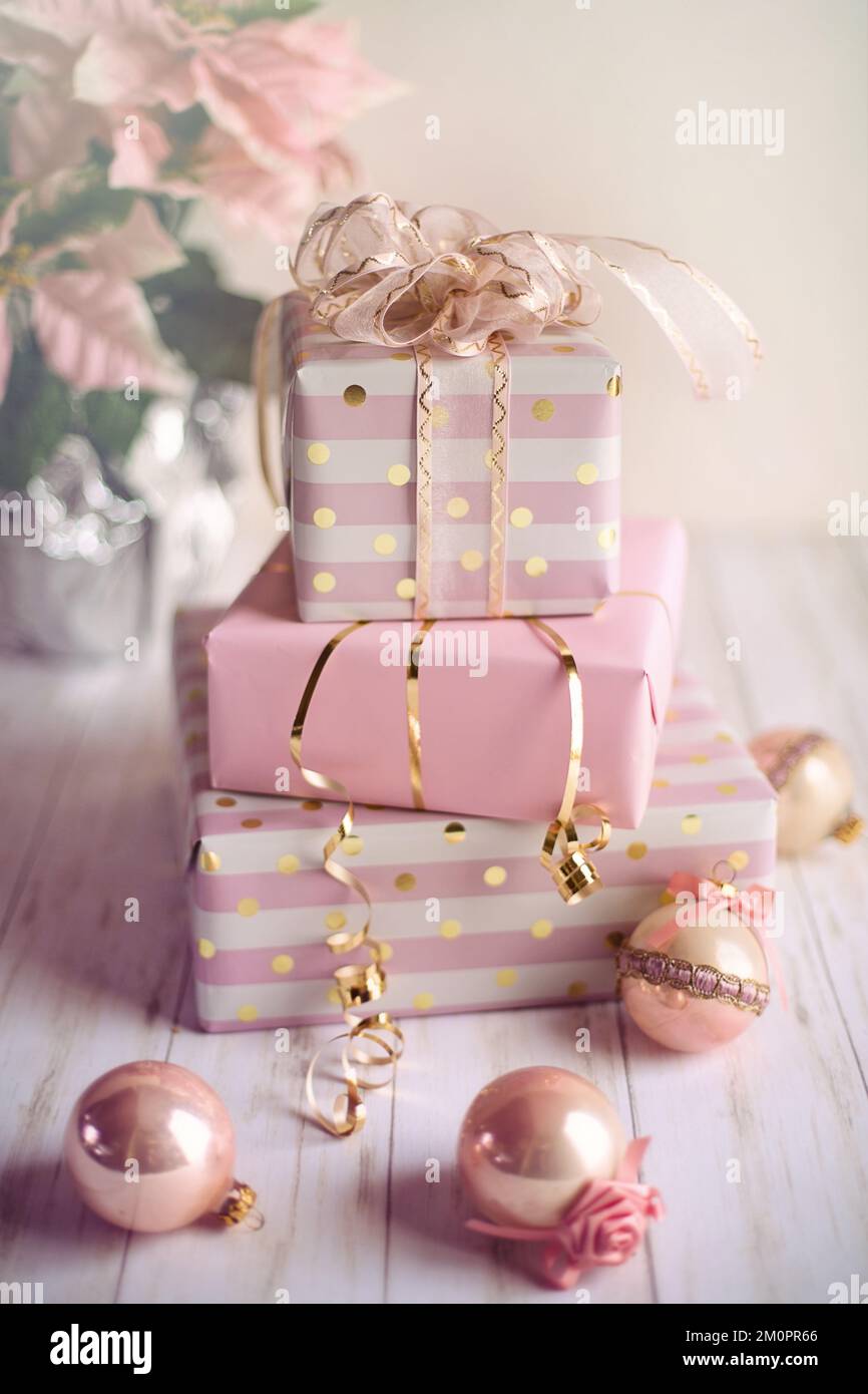 Una vertical de cajas de regalo rosadas en la mesa decorada con bolas de Navidad Foto de stock