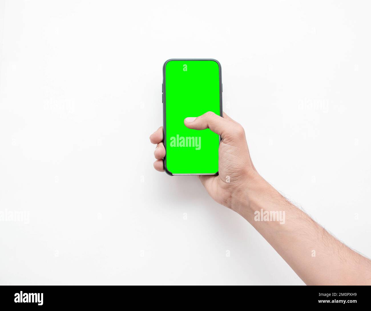 La mano de un hombre sosteniendo su teléfono inteligente con pantalla verde sobre un fondo blanco aislado Foto de stock