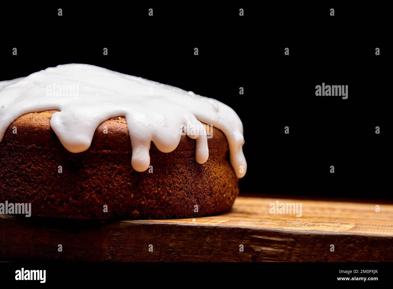 Un primer plano de pastel marrón oscuro con crema blanca sobre madera sobre fondo negro Foto de stock