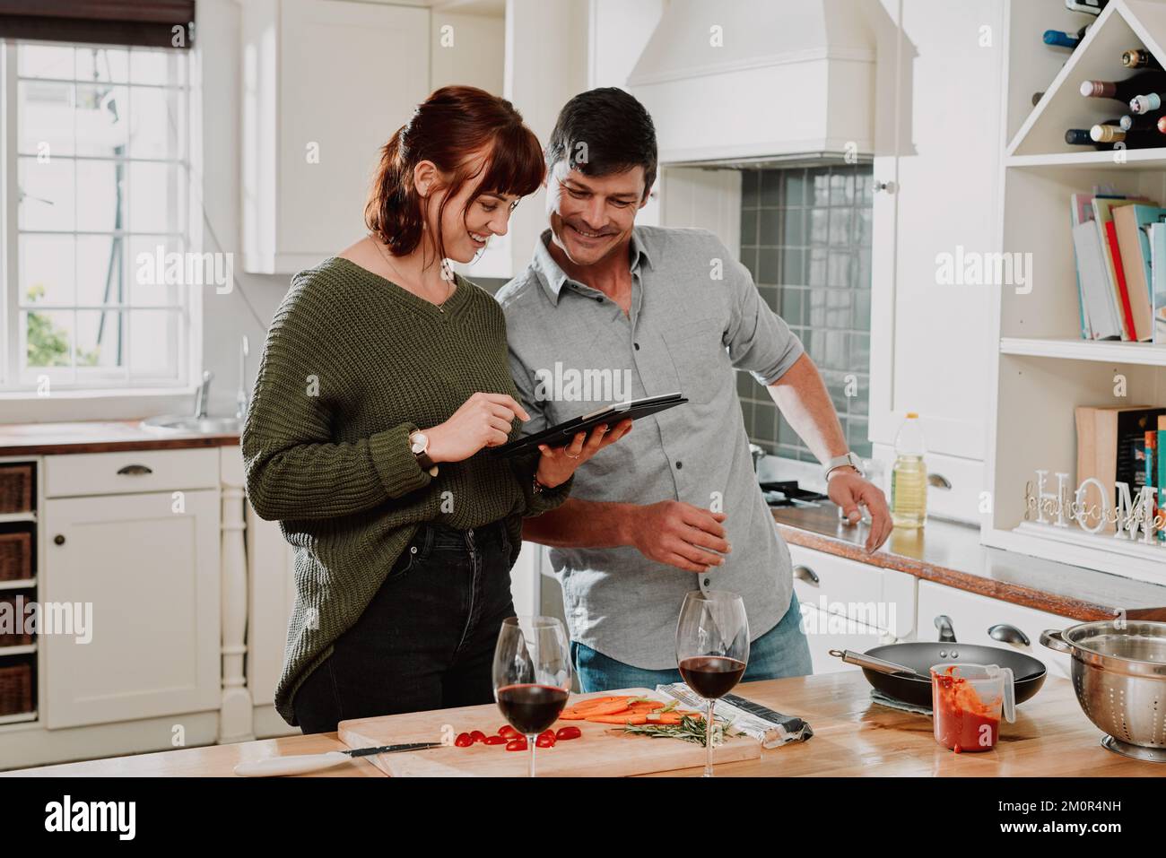 Esta receta es tan fácil de seguir. una pareja usando una tableta digital mientras cocina en casa. Foto de stock
