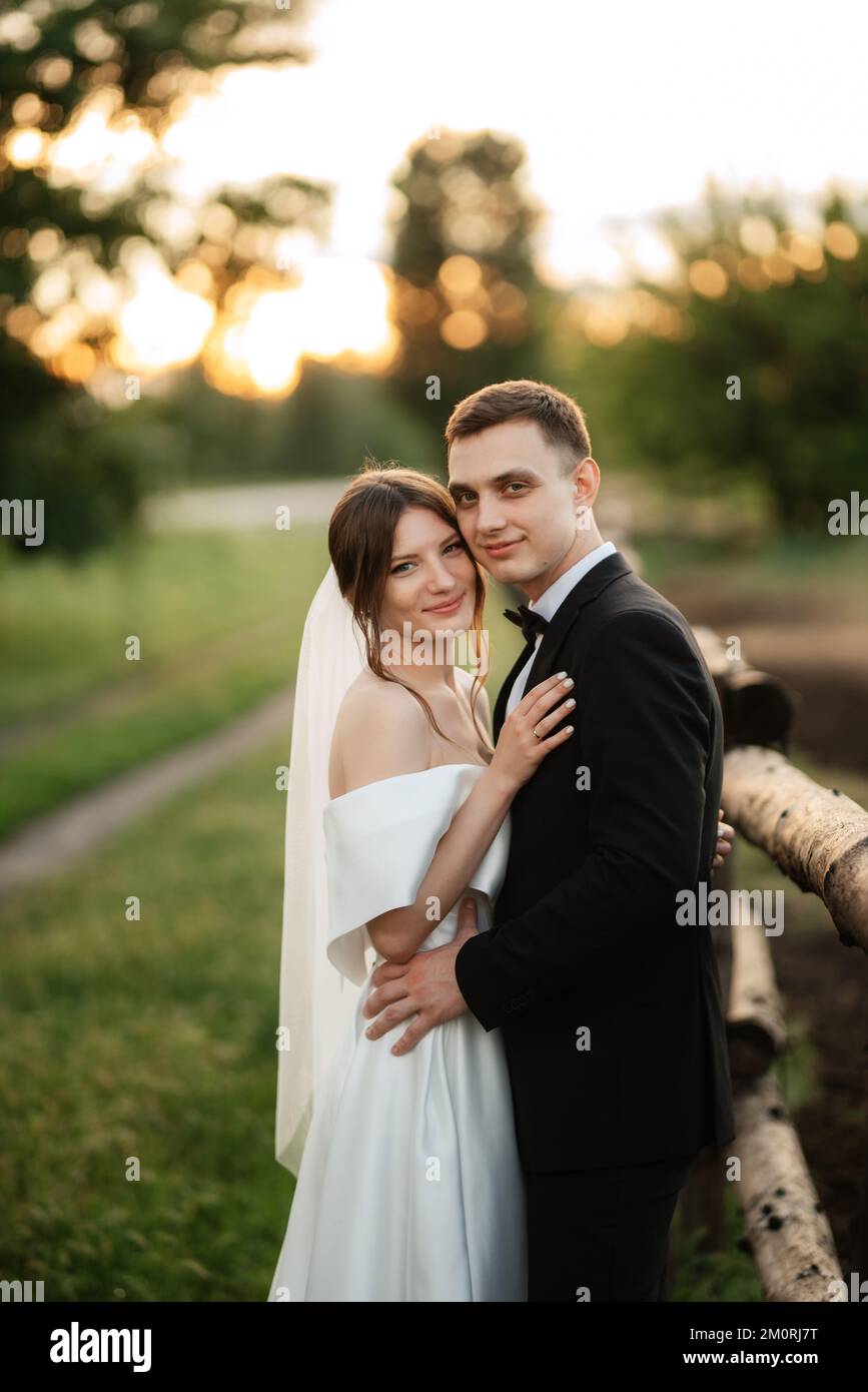 joven pareja el novio en un traje negro y la novia en un vestido corto  blanco en un paseo por el pueblo Fotografía de stock - Alamy