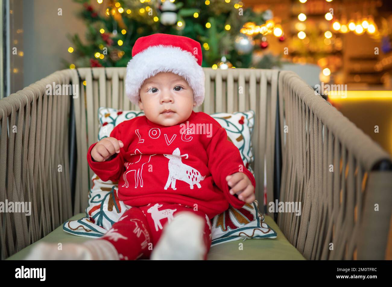 Lindo bebé recién nacido con sombrero de Santa Claus y conjunto festivo  junto a un árbol de Navidad con decoración festiva y luces de ferry para  Año Nuevo y Navidad Fotografía de