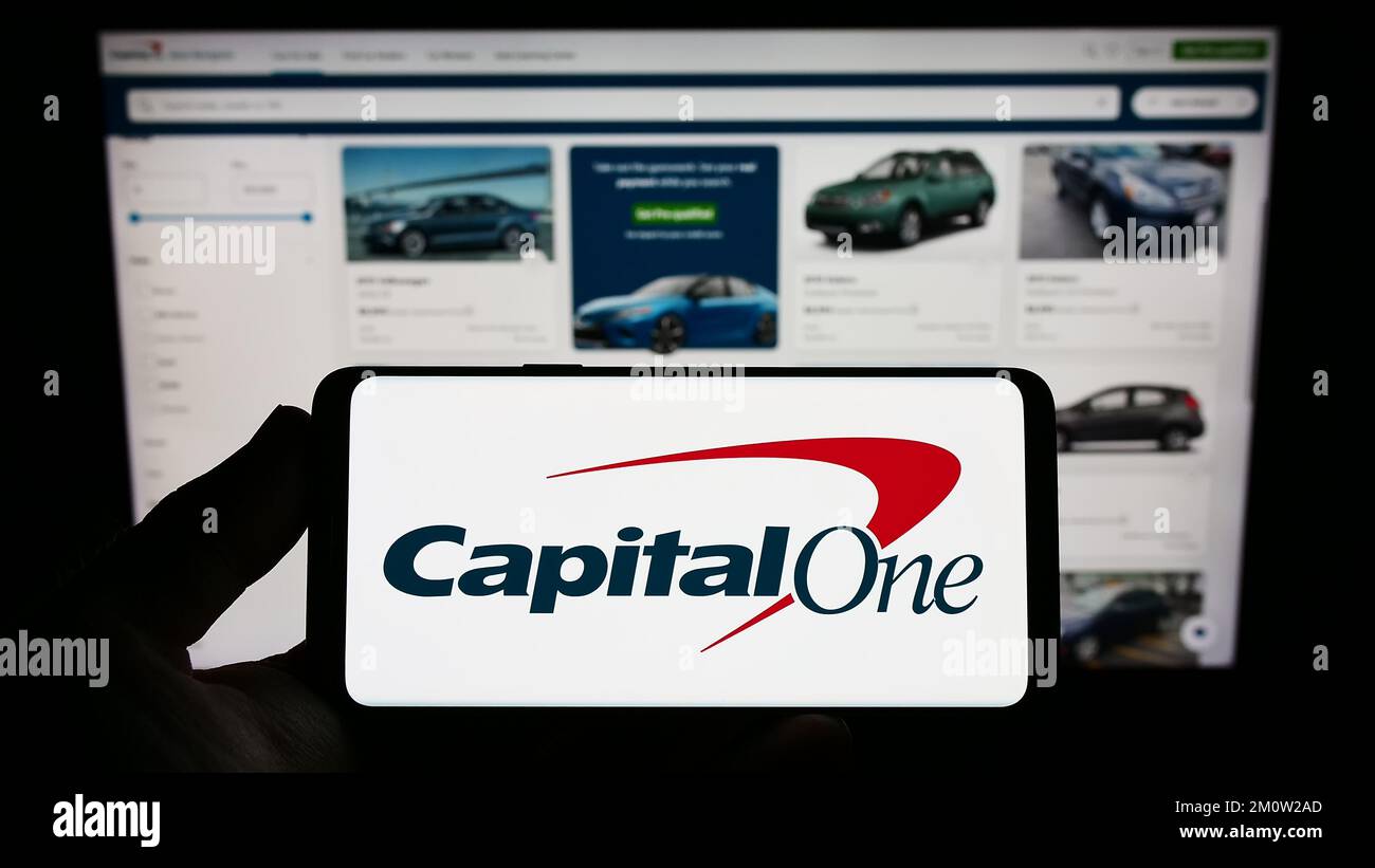 Persona que tenga un smartphone con el logotipo de la empresa estadounidense Capital One Financial Corporation en la pantalla delante del sitio web. Enfoque la pantalla del teléfono. Foto de stock
