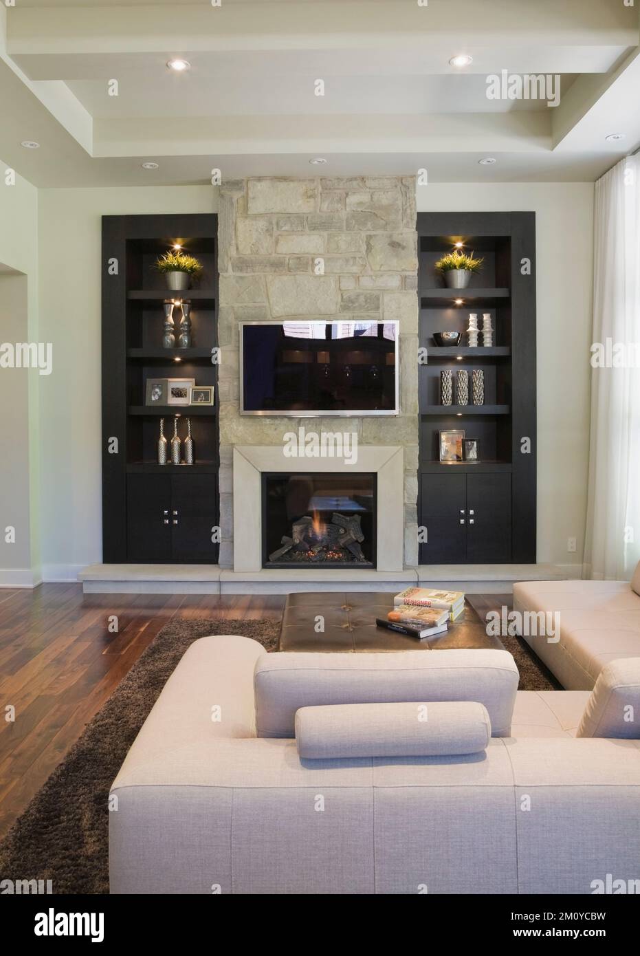 Unidad de pared negra con chimenea de piedra natural y sofá seccional en la  sala de estar dentro de una casa de lujo Fotografía de stock - Alamy