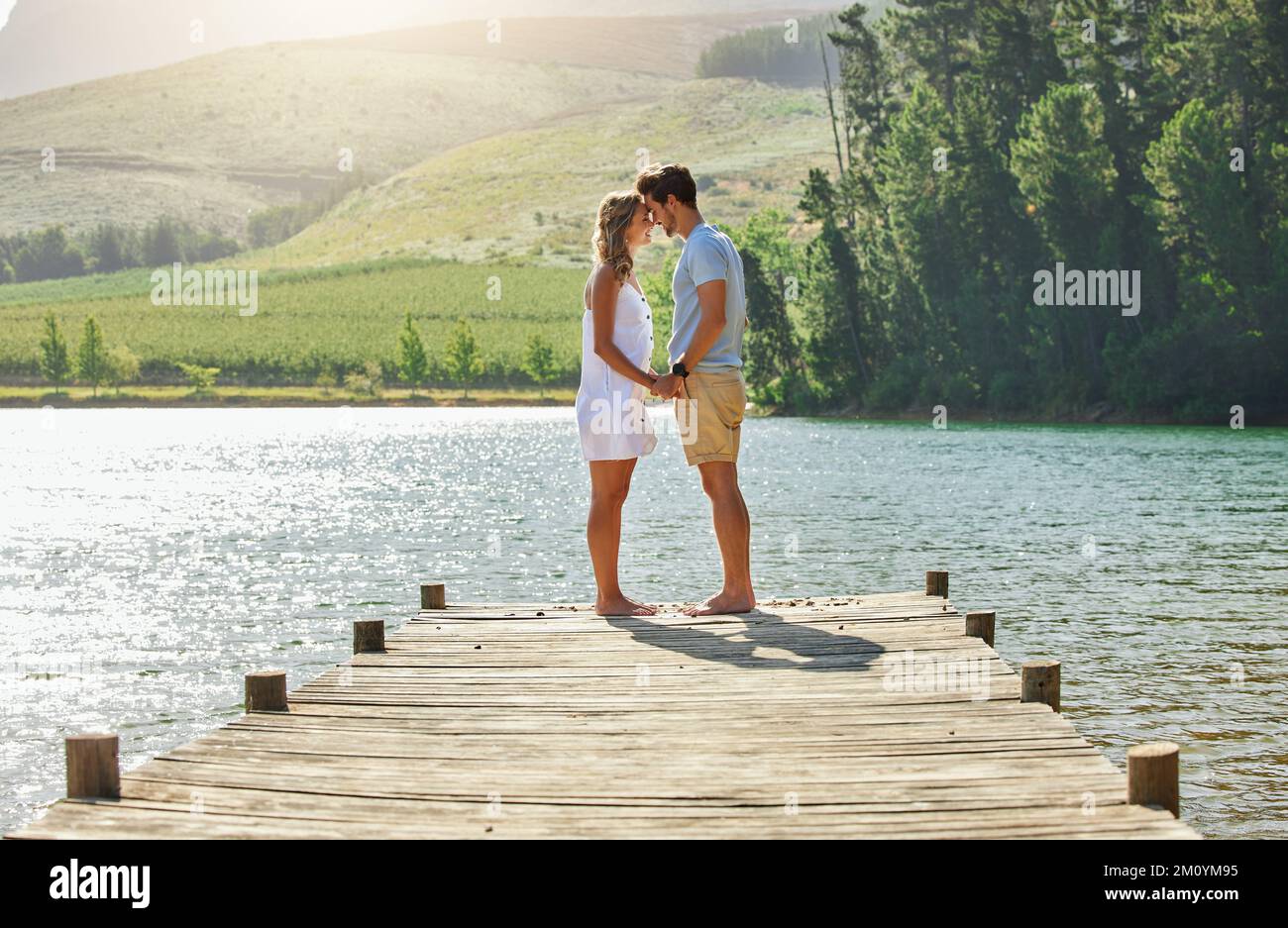 En cualquier lugar con usted se siente como el mejor lugar para estar. una joven pareja de enlace mientras está de pie en un embarcadero en un lago. Foto de stock