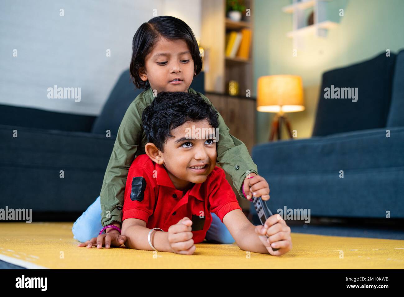 Hermanos pequeños niños luchando por el mando a distancia mientras ven la televisión o la televisión en casa - concepto de estilo de vida de la infancia, los hermanos pelean y. Foto de stock