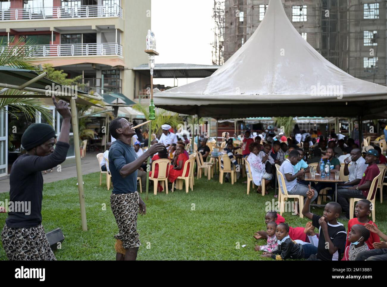KENIA, Nairobi, clase media en jardín de cerveza, actuación acrobática / KENIA, Nairobi, Mittelklasse im Biergarten, akrobatische Vorführung zur Unterhaltung der Gäste Foto de stock