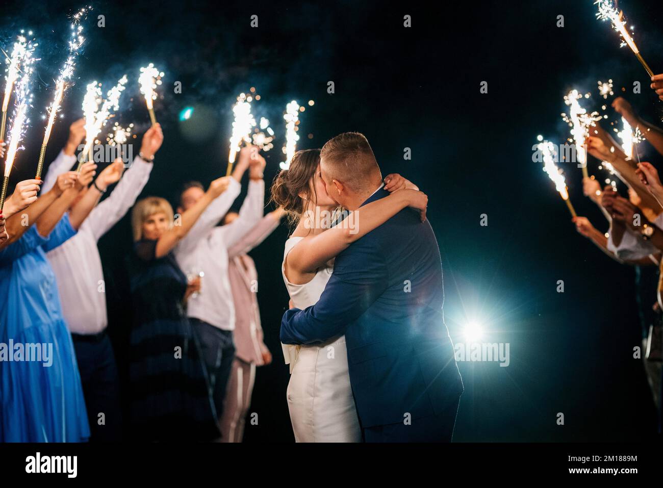 Fuego frío de velas de pastel y fuegos artificiales en manos de las  personas que rodean a los recién casados.