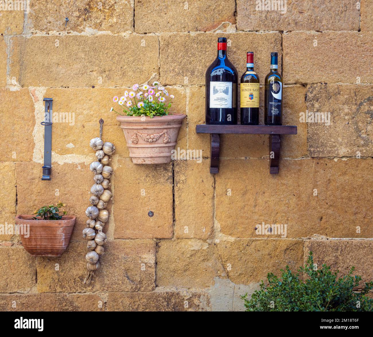 Pienza, provincia de Siena, Toscana, Italia. Ajo, flores y botella de vino vacía fuera del restaurante. Foto de stock