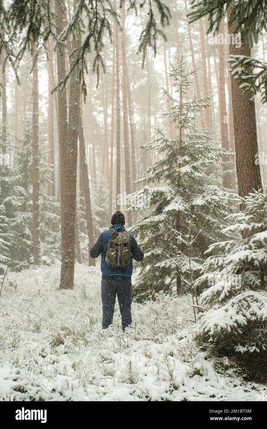 Viajes y senderismo en invierno season.man con una mochila en el tiempo nevado. Nevadas en el bosque. Hombre en el medio ambiente natural en la estación fría. Foto de stock